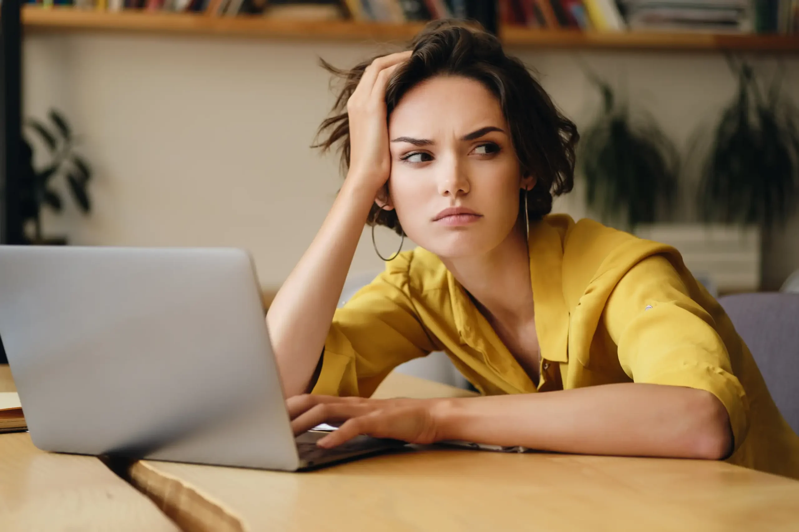 Kobieta odczuwająca stres i przeciążenie podczas pracy przy laptopie